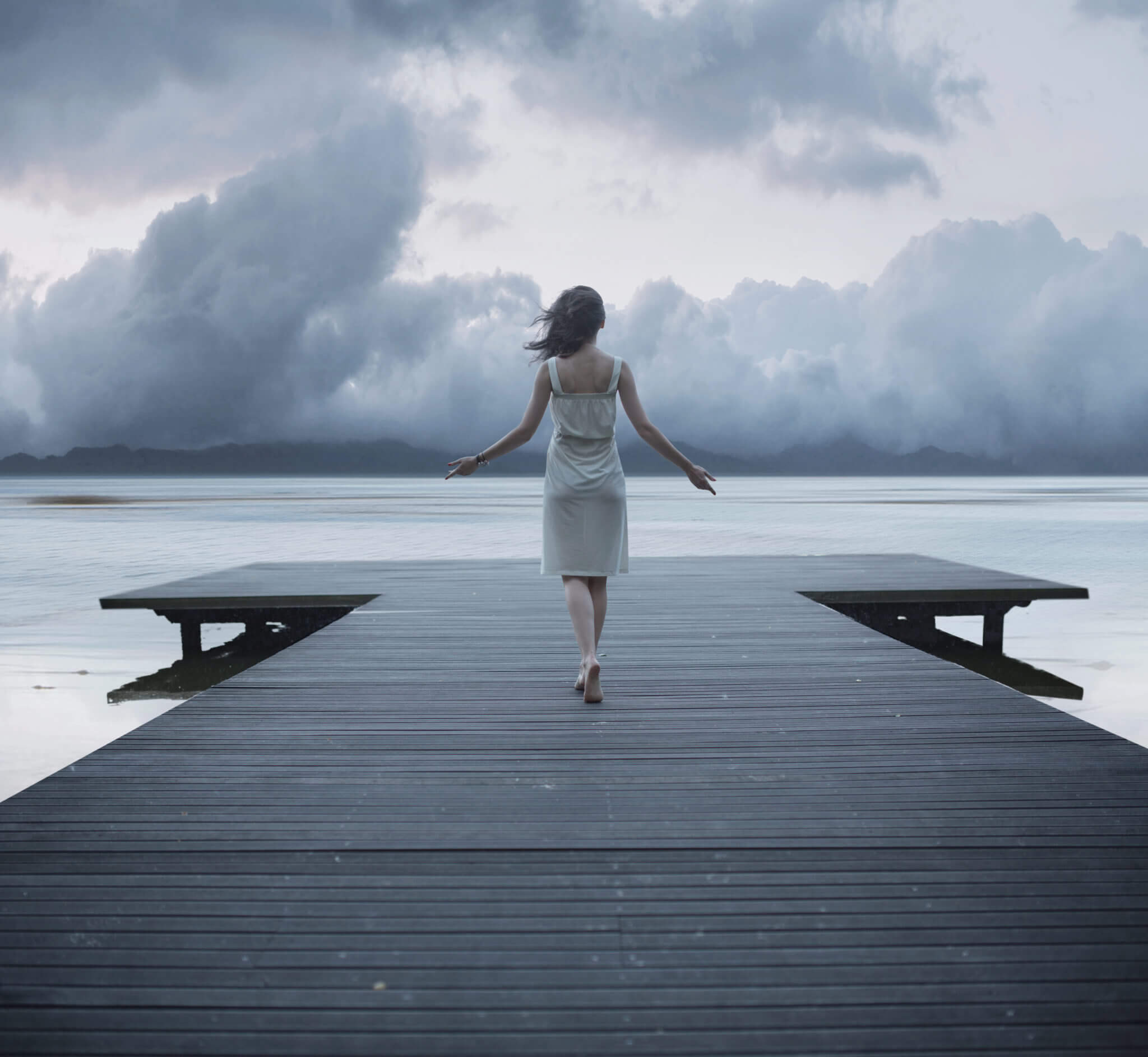Woman walking on a dock towards a lake.